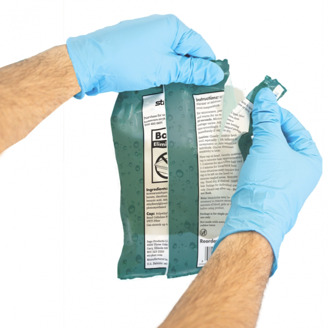Caregiver wearing gloves tearing open the packaging of Comfort Rinse Free Shampoo Cap