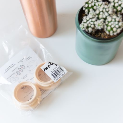 Motif Medical Wide Bottle Adapters shown in packaging on table with plant