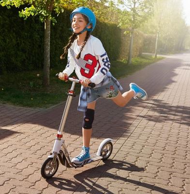 Girl riding scooter wearing Actimove Kids Knee Support Open Patella