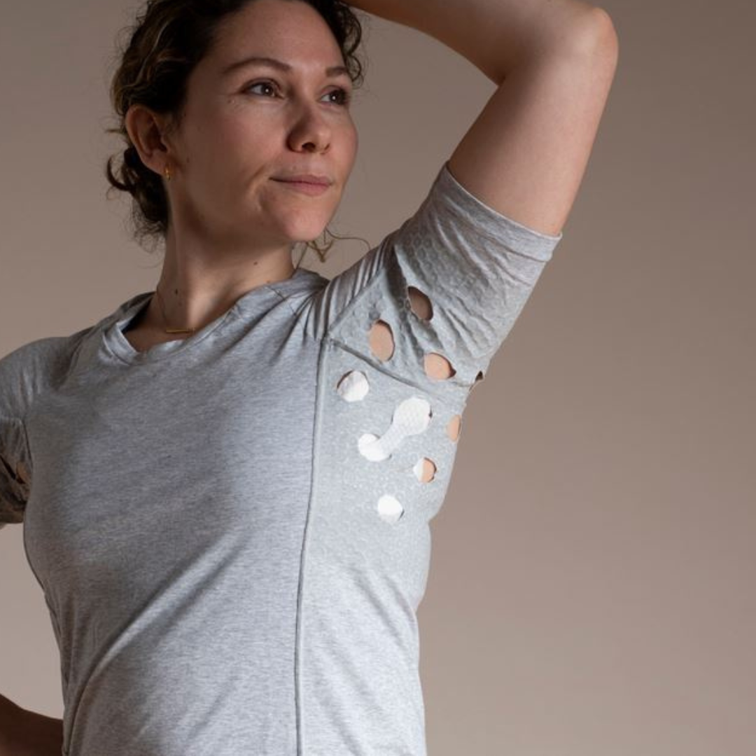 Woman wearing HidraWear AX T-shirt with arm raised to show the underarm area where HidraWear Dressing is placed