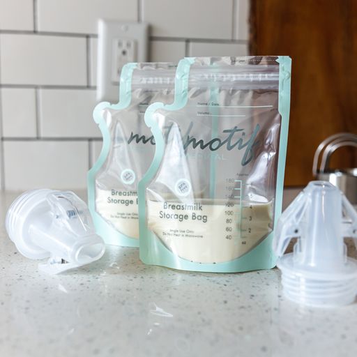 Motif Medical Pump-To-Bag Adapter shown on a counter with Motif Medical Breastmilk Storage Bags containing breastmilk