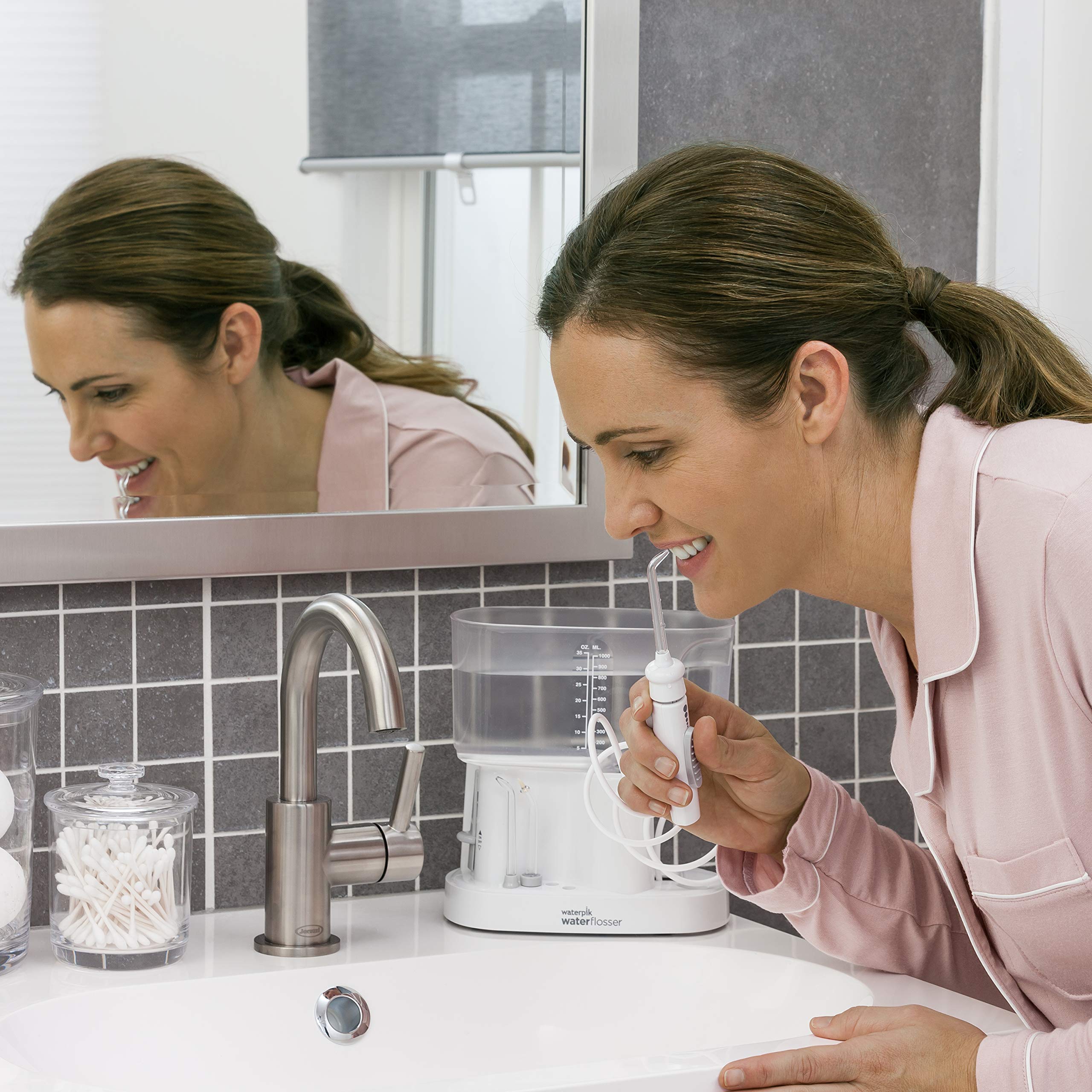 Woman Leaning Over Sink Using Waterpik Classic Professional Water Flosser
