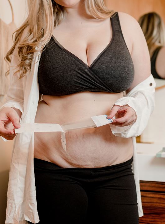 Woman unwrapping Motif Medical C Section Bandage from the Motif Medical C Section Bandage System Stages 1,2,3