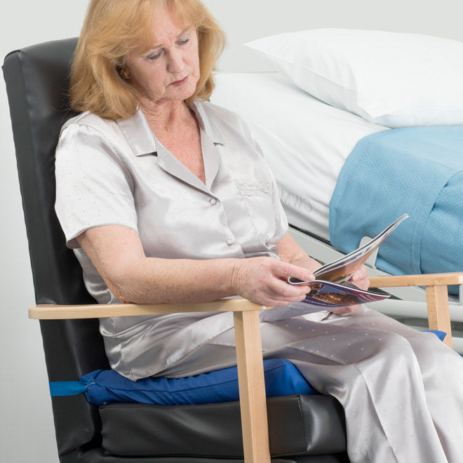 Woman Reading At The Bedside Seated On Inflated Repose Cushion