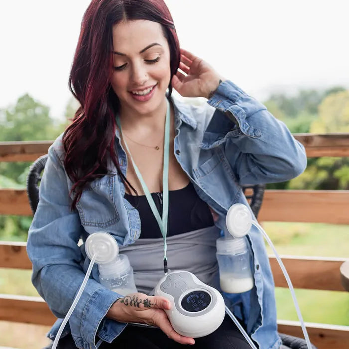 Woman sitting outside wearing Hands-Free Pumping Bra and using Motif Medical Duo Breast Pump