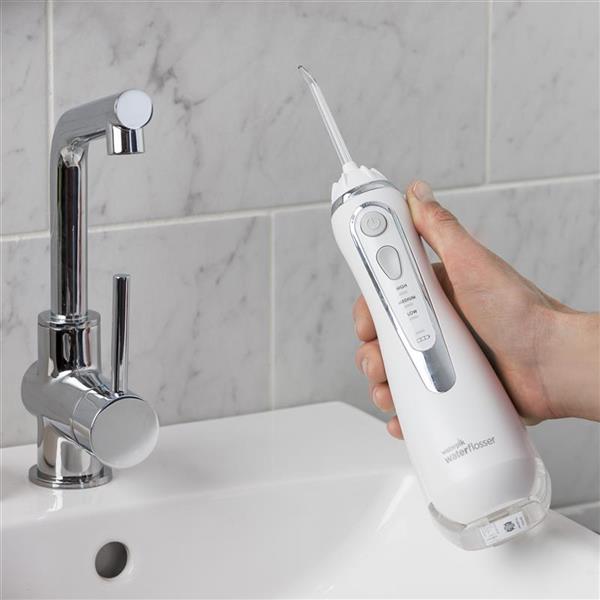 Hand holding Waterpik Cordless Advanced Water Flosser in Pearly White